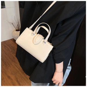 Détail d'un sac à main en cuir mat crème avec doubles anses porté par un mannequin
