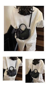 Détail du sac seau noir demi-lune avec foulard à pois sur un escalier intérieur
