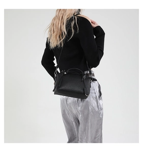 Rückansicht eines Modells mit schwarzer Handtasche in Litschistruktur und Faltenhose