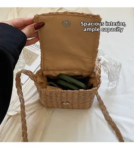 Detail view of woven straw crossbody bag showing magnetic buckle and spacious interior