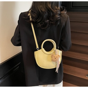 Close-up of yellow half-moon crossbody bag with cute bear charm on model back