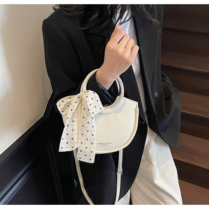 Détail du sac croissant blanc crème avec texture grainée et foulard à pois décoratif