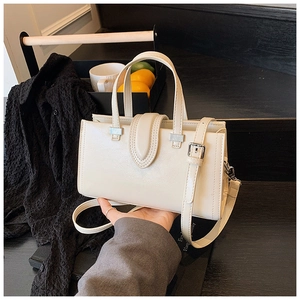Détail d'un sac à main en cuir blanc crème avec boucles argentées et bandoulière réglable