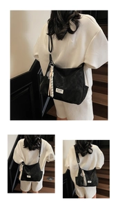 Detail of black tote bag with white logo patch and decorative tennis racket tassel
