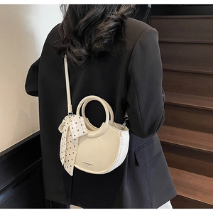 Détail du sac seau crème en cuir grainé avec foulard à pois et bandoulière élégante
