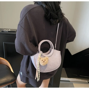 Detail of light purple semi-circular bucket bag with plush bear charm and rope tassel