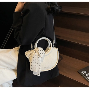 Détail du sac à main blanc en cuir grainé avec un ruban de soie à pois noir et blanc