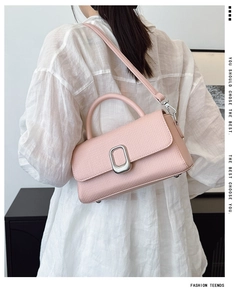 Detail view of pink lychee textured leather square bag with silver metal clasp on model