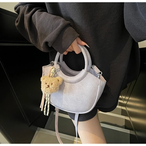 Detail of lavender textured leather bucket bag featuring a small brown plush bear charm