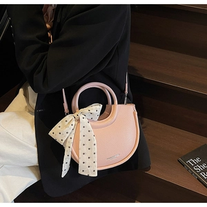 Sac seau demi-lune en cuir litchi rose avec nœud à pois et détails de poignée ronde