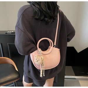 Rear view of pink half-moon crossbody bag with plush bear charm and silk ribbon decor