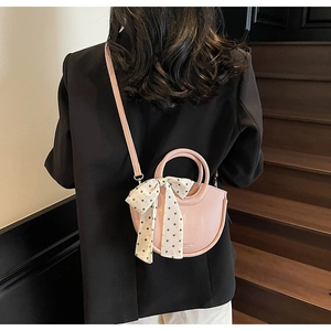Sac seau rose en cuir grainé avec foulard à pois porté par un mannequin chic
