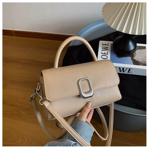 Macro view of beige leather bag featuring a silver square buckle and smooth top handle