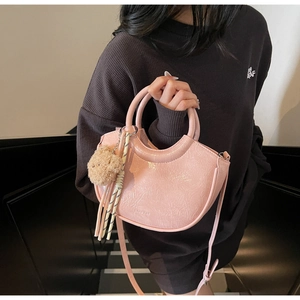 Pink crescent crossbody bag in wrinkled patent leather with plush bear charm on model