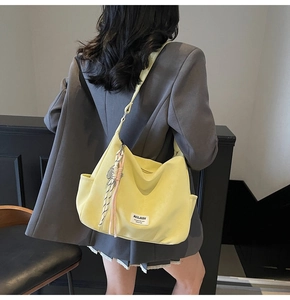 Detail of yellow leather tote bag featuring colorful woven tassels and brand label