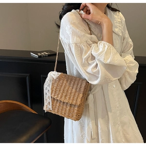 Detailed shot of a straw woven crossbody bag featuring delicate white lace trim and floral texture