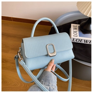 Detailed view of light blue woven texture and silver buckle on a square handbag