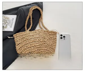 Detail view of woven straw bag showing texture and size comparison with a mobile phone