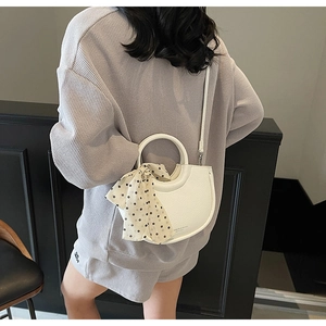 Détail du sac demi-lune en cuir blanc avec foulard à pois et bandoulière amovible