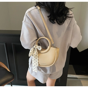 Détail du sac demi-lune beige en cuir grainé avec un foulard en soie à pois élégant
