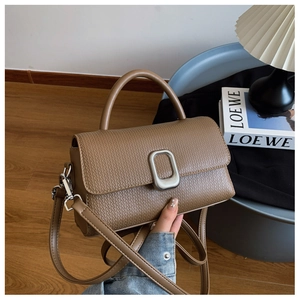 Close-up of textured tan leather handbag with silver clasp and top handle for women