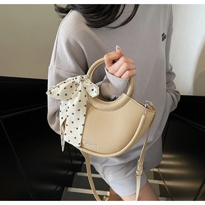 Détail du sac seau demi-lune beige avec texture grainée et foulard à pois décoratif