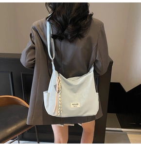Detail view of light blue soft leather tote bag with stylish tassel charm and brand label