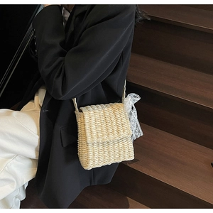 Detailed view of the woven straw crossbody bag featuring romantic white lace bow details