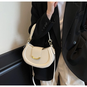 Detail of cream lychee texture saddle bag with gold metal buckle on black blazer