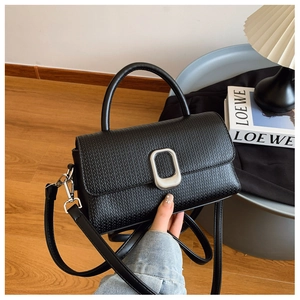 Detail of black textured PU leather handbag with silver oval buckle and top handle