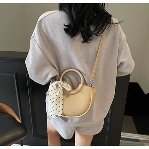 Détail du sac seau beige avec foulard à pois et texture cuir grainé lychee