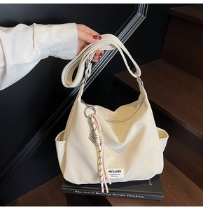 Detail view of cream PU leather tote bag with woven strap charm and brand tag