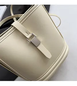 Détail d'un sac seau beige montrant le grain de cuir et la boucle en métal argenté