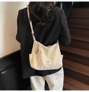 Detail of off-white canvas tote bag featuring tennis racket charm and brand label
