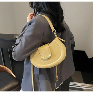 Detail of light yellow lychee pattern saddle bag with elegant gold metal ring buckle