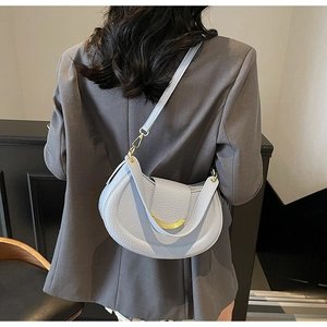 Litchi pattern saddle bag in light grey-blue shown on shoulder with blazer suit