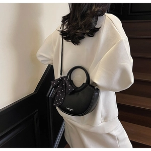 Détail du sac seau noir en demi-lune avec texture grainée et accessoire foulard à pois