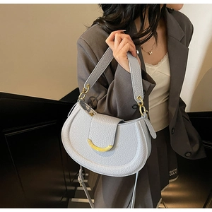 Close-up of litchi texture light blue saddle bag with elegant golden moon buckle hardware