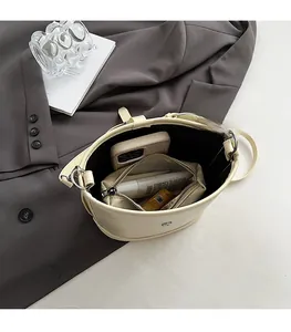 Vue de dessus montrant l'intérieur spacieux du sac seau en cuir beige avec boucles en métal