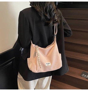 Detail showing the pink nylon tote bag with brand label and side pocket on stairs