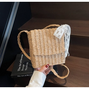 Close-up of beige woven straw shoulder bag with delicate white lace bow detail