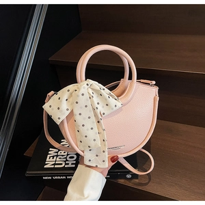 Détail d'un sac à main demi-lune rose clair avec foulard à pois sur escalier en bois