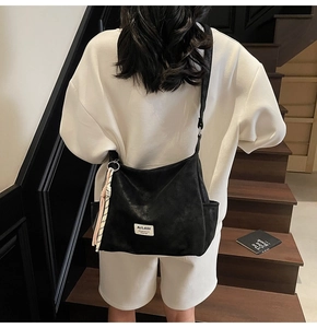 Detail of black large tote bag with woven pendant and adjustable strap on model