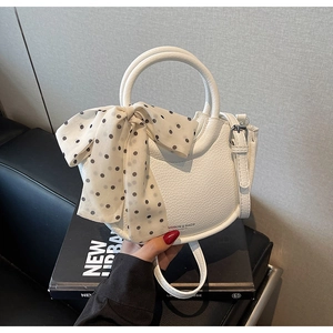 Détail du sac seau en cuir grainé blanc avec foulard à pois et poignée ronde
