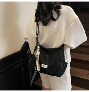 Detail of black Hobo tote bag showing textured material and tennis racket charm