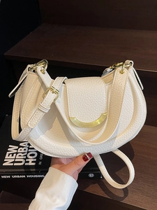 Chic white lychee pattern saddle bag with gold hardware on a modern wooden background