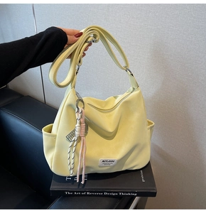 Detail of light yellow tote bag featuring adjustable shoulder strap and woven MULAIDI label