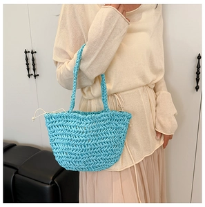 Detail of hand-woven blue straw bucket bag featuring a secure cream drawstring liner