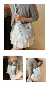 Détail du sac seau bleu clair avec boucle décorative et deux options de bandoulière