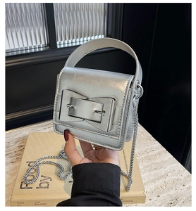 Macro detail of silver mini square bag featuring oversized buckle and metallic chain strap